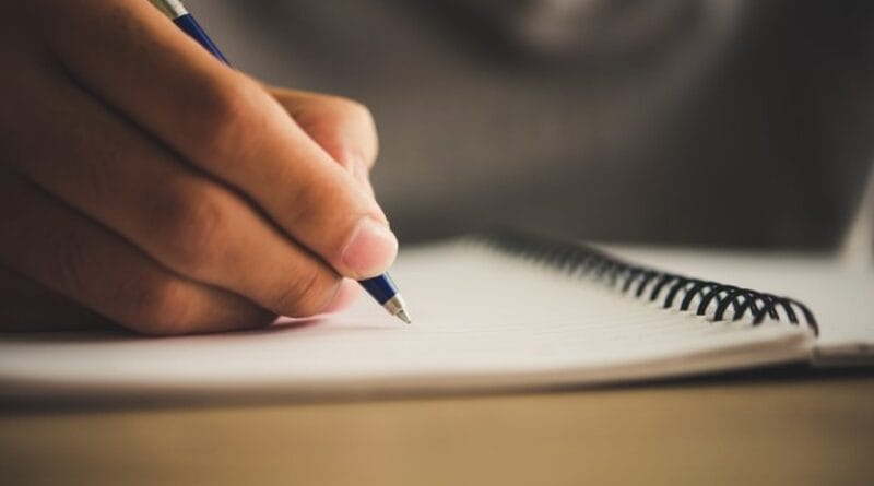 Um pessoa escreve de lápis em um caderno